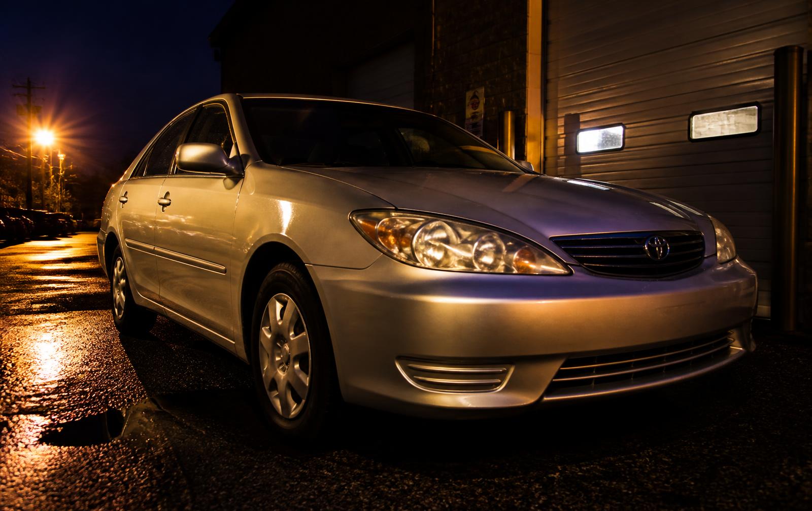Silver used Toyota Camry parked outside a Georgia rental garage at dusk